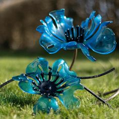 two blue glass flowers sitting in the grass