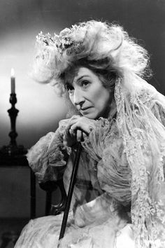 an old black and white photo of a woman in a wedding dress holding a cane