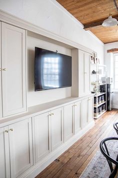 a flat screen tv mounted to the side of a white wall in a living room