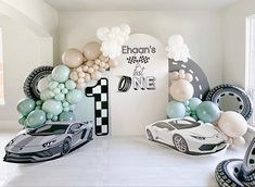 a room filled with balloons and cars on the floor next to a wall that reads 1