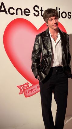 a man standing in front of a sign with a heart on it's wall