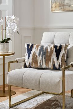 a white chair with a blue and brown pillow on it