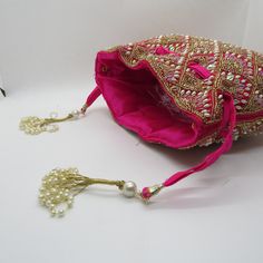 rani pink fabric pearl beaded the shining handbag drawstring purse potli bag for woman | indian wedding purse and potli gifting giveaways Designed with the heart, this beautiful Potli or batawa bag are eye catchy and made of premium material. Key Features: Embroidery art work This potli is good match with both Indian and western outfits and are superb for wedding and festive parties This would be best complement to your designer saree, lenhga or any other kind of dress This is the combination of Handmade Potli Bag For Party And Festivals, Festive Mirror Work Clutch As A Gift, Gold Potli Bag With Mirror Work For Gift, Pink Shoulder Bag With Handwork For Party, Festive Mirror Work Pouch Potli Bag, Festival Dori Work Potli Bag For Party, Festive Mirror Work Potli Pouch Bag, Bollywood Dori Work Potli Bag For Party, Bollywood Style Dori Work Potli Bag For Party