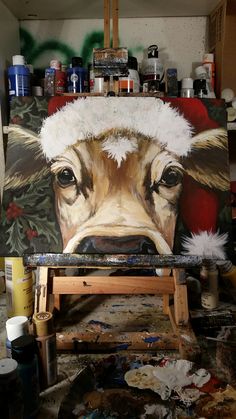 a painting of a cow with a santa hat on it's head in a studio