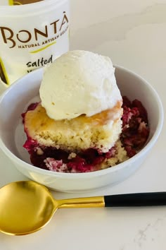 a white bowl filled with ice cream next to a gold spoon and cup of coffee