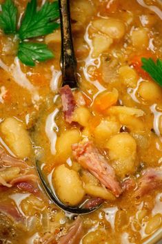 a close up of a bowl of soup with beans and ham on top, garnished with parsley