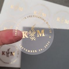 a person holding up a sticker that says thank you're celebrating with gold lettering