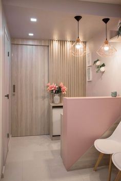 a pink and white room with two chairs next to the counter, flowers in vases