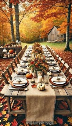 a long table with place settings and fall leaves on the ground in front of it