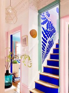 blue and pink staircase leading up to the second floor with potted plants on either side