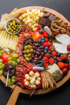 a wooden platter filled with cheese, fruit and crackers