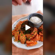 a white plate topped with fried food next to a small bowl of ranch dressing on top of it