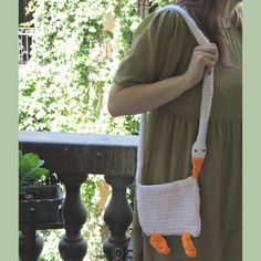 a woman is holding a crocheted bag with an orange and white bird on it