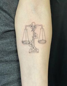 a tattoo on the arm of a woman with a balance scale and flowers in it