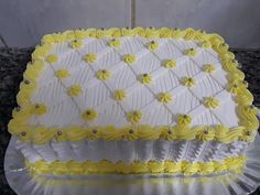 a white and yellow cake sitting on top of a glass plate covered in icing