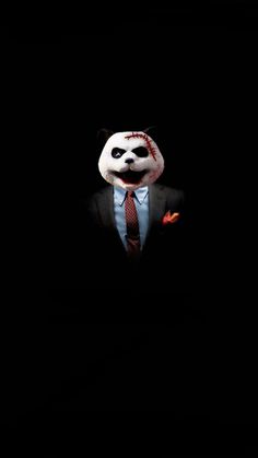 a man in a suit and tie with a panda mask on his face, standing in the dark