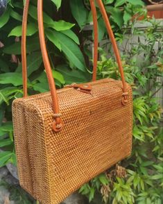 a brown woven purse hanging from a tree