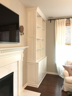 a living room with a fireplace, tv and bookshelf next to a window