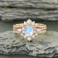 an opal and diamond ring sitting on top of a rock