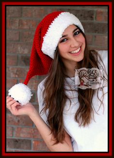 a young woman wearing a santa hat and holding a pom - pom in her hand