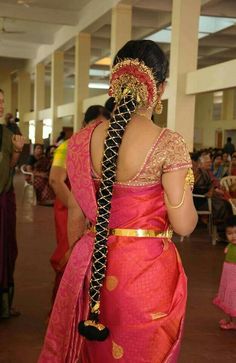 a woman in a red and gold sari with her back turned to the camera