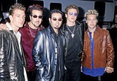 four men in leather jackets and sunglasses posing for the camera with one man looking at the camera