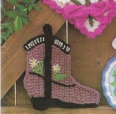 two crocheted boots are hanging on a clothes line next to a pot holder