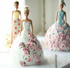 there are two barbie dolls standing next to each other on the table with flowers in front of them