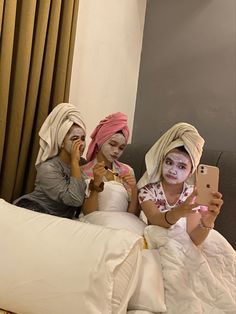 three women sitting on a bed with their faces painted