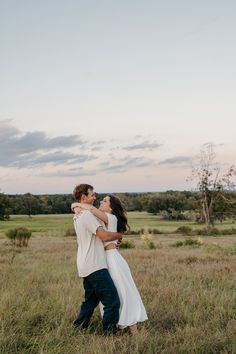 a man and woman hugging in the middle of a field