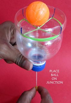 a hand holding a plastic ball in a wine glass filled with water and string attached to it