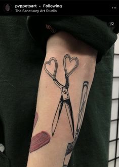 a person with a tattoo on their arm has scissors and hearts in the shape of heart