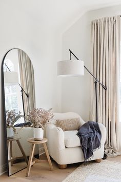 a living room filled with furniture and a large mirror on the wall next to a window