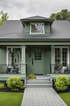 a green house with two front porches and landscaping