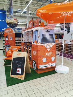 an orange food truck is on display in a store with umbrellas and chairs around it