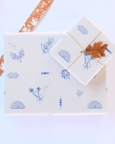 a gift wrapped in blue and white paper with a maple leaf on the top, sitting next to it