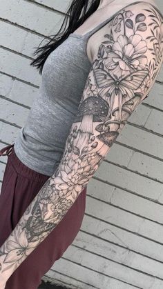 a woman's arm with flowers and butterflies tattooed on her left arm, in front of a white brick wall