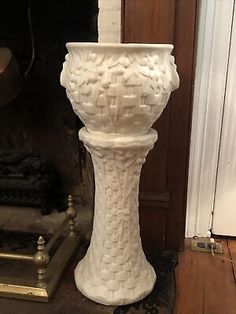 a white vase sitting on top of a wooden floor next to a fire hydrant