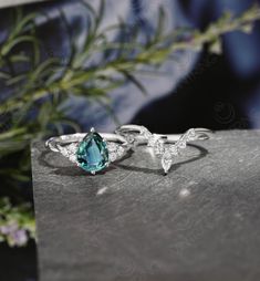 two rings with blue and white topazte stones on a stone table next to flowers