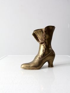 "This is a mid 20th century brass vase shaped as a Victorian woman's boot. Wonderful detailing to the solid brass.  CONDITION In good condition with wear consistent with age and use.  MEASUREMENTS Height:  8.75\"  .. 22.2 cm Length:  7.75\"  ..  19.7 cm Width:  4.25\"  ..  10.8 cm 112337" Victorian Shoes, Brass Vase, Woven Baskets Storage, Vase Shapes, Victorian Women, Vintage Studio, Cool Mugs, Solid Brass, 20th Century