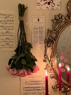 a mirror and some flowers on a wall with sheet music notes hanging from it's sides