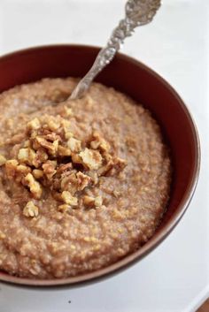 a bowl of oatmeal with walnuts and a spoon in the bowl