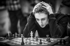 a man sitting at a chess board with his hands on his head while playing the game