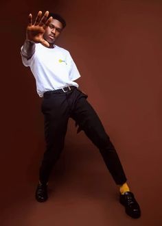 a man in white shirt and black pants doing a hand sign