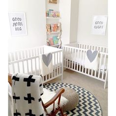 a baby's room with two cribs and a rug on the floor