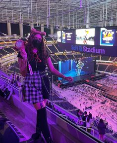 a woman wearing a costume and holding a microphone in front of an arena filled with people