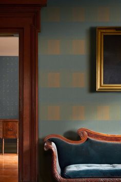 a blue couch sitting in front of a painting on the wall next to a doorway