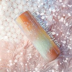 a colorful tumbler sitting on top of a fur covered floor next to a pink blanket