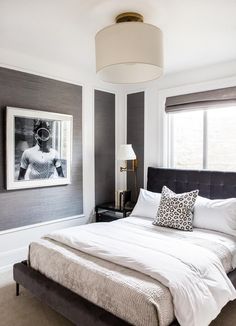 a large bed sitting in a bedroom next to a window with two pictures on the wall