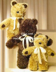 three teddy bears sitting on top of a white table next to each other and one has a bow around its neck